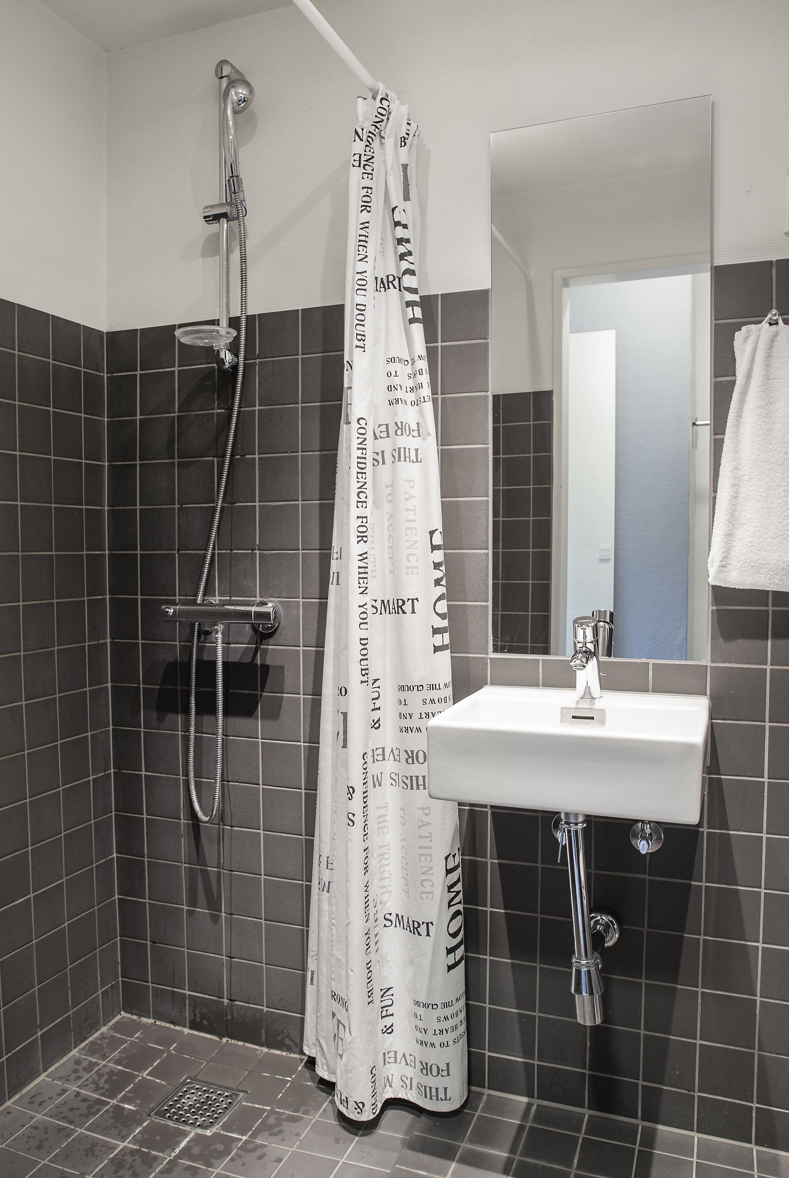 Un baño con ducha, lavamanos y espejo.
