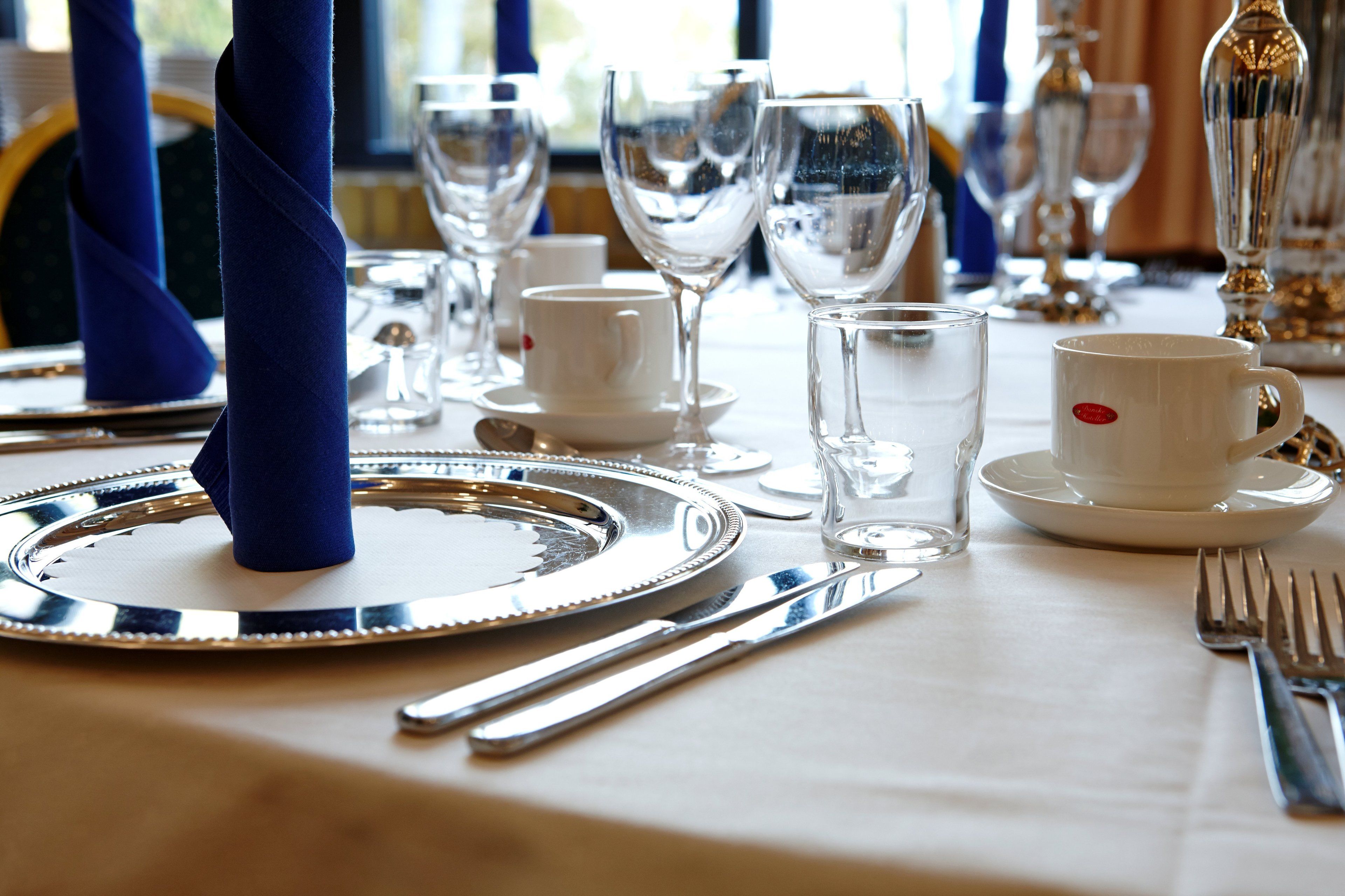 A table set with white plates, silverware, and clear glassware, including a water glass and a wine glass.