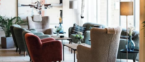 A modern living room with a sofa, armchairs, and a coffee table. There is a large abstract painting on the wall and a floor lamp.
