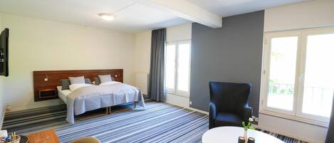 Una habitación de hotel con cama, una silla, una mesa y una ventana.
