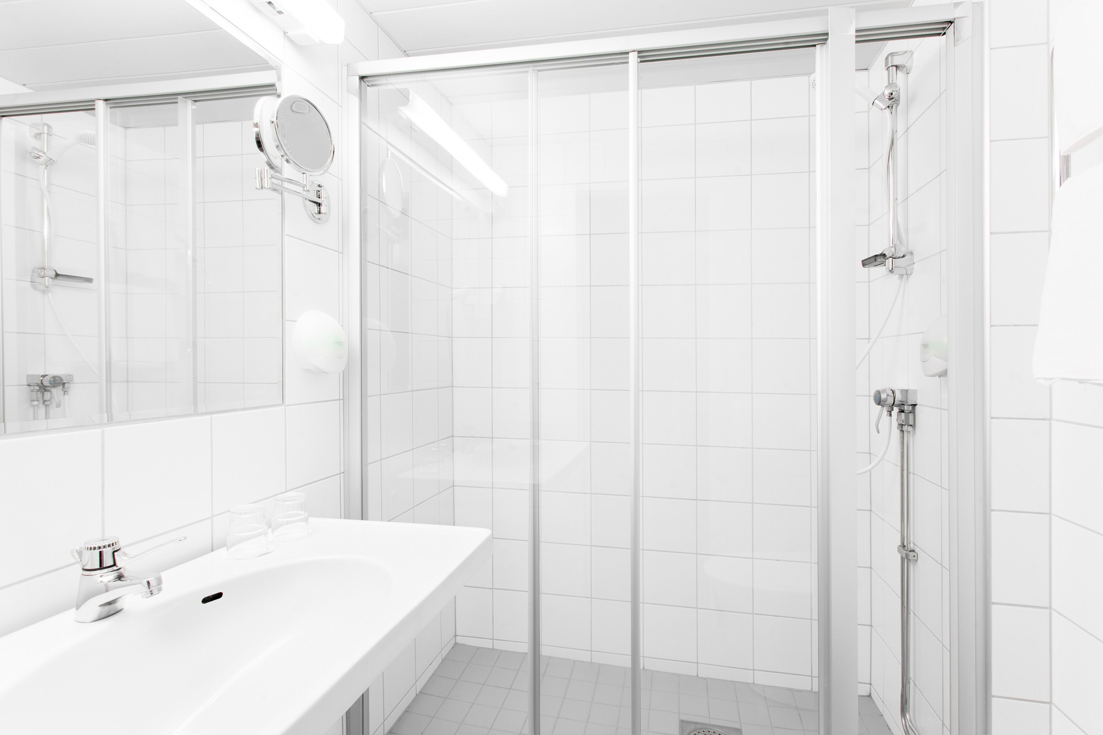 A modern bathroom with a white sink, a mirror, and a glass shower enclosure.