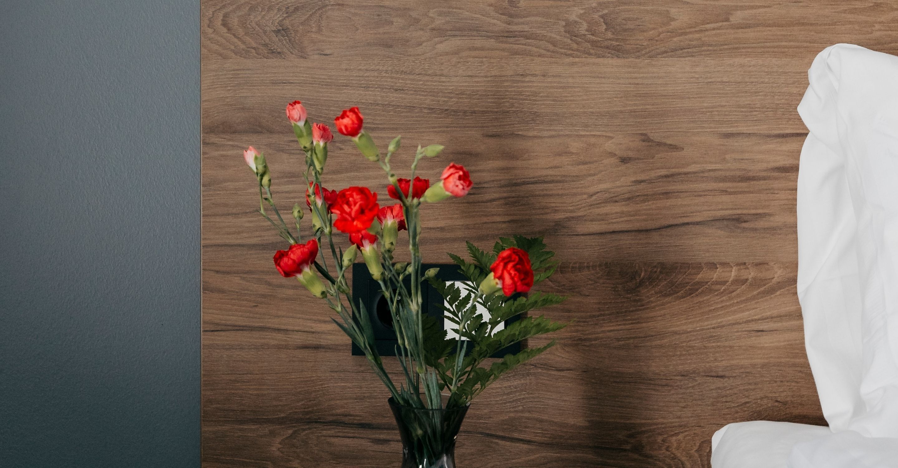 A vase with red flowers on a wooden surface.