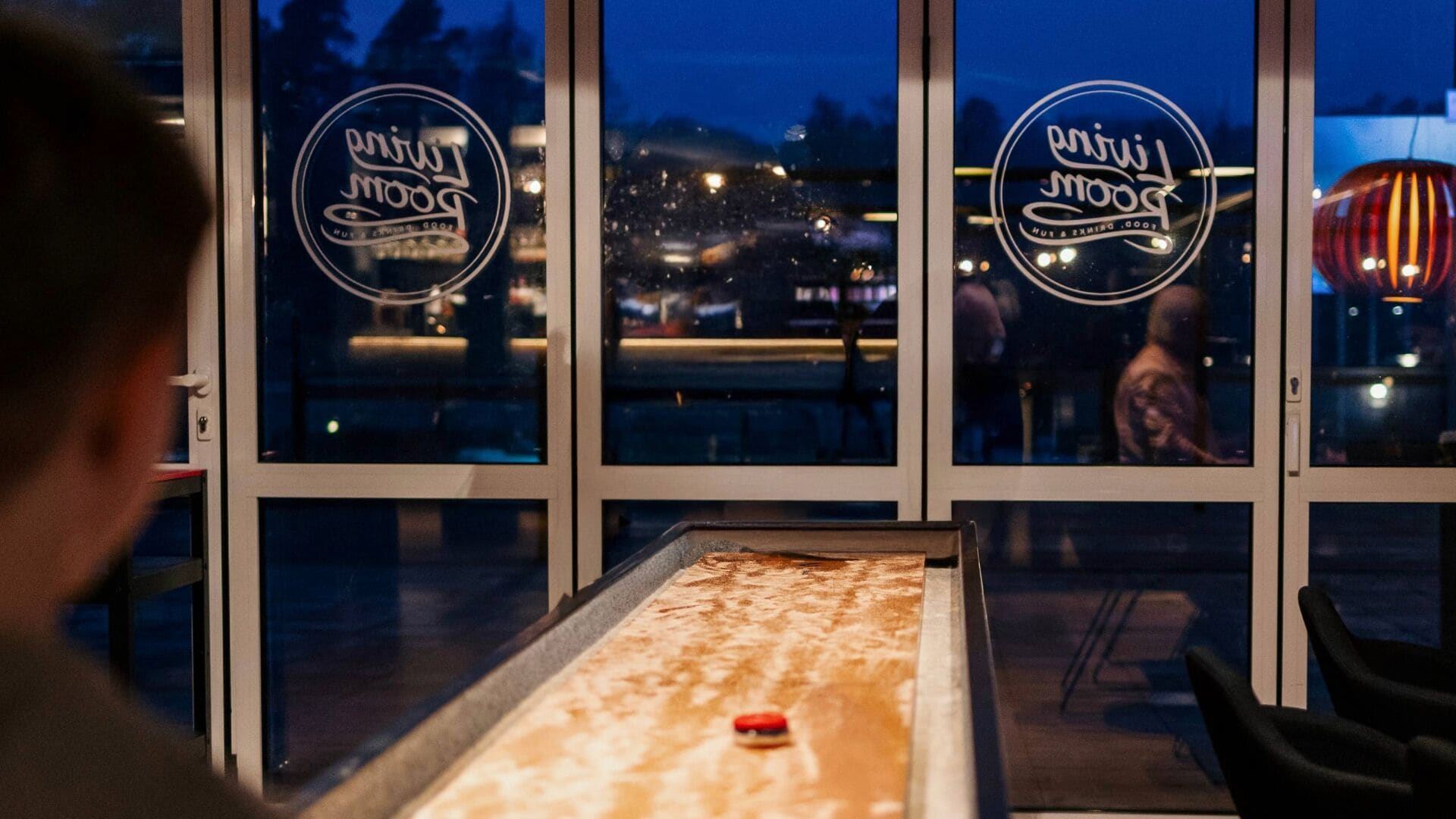 A table with a dessert in front of a window with a logo.