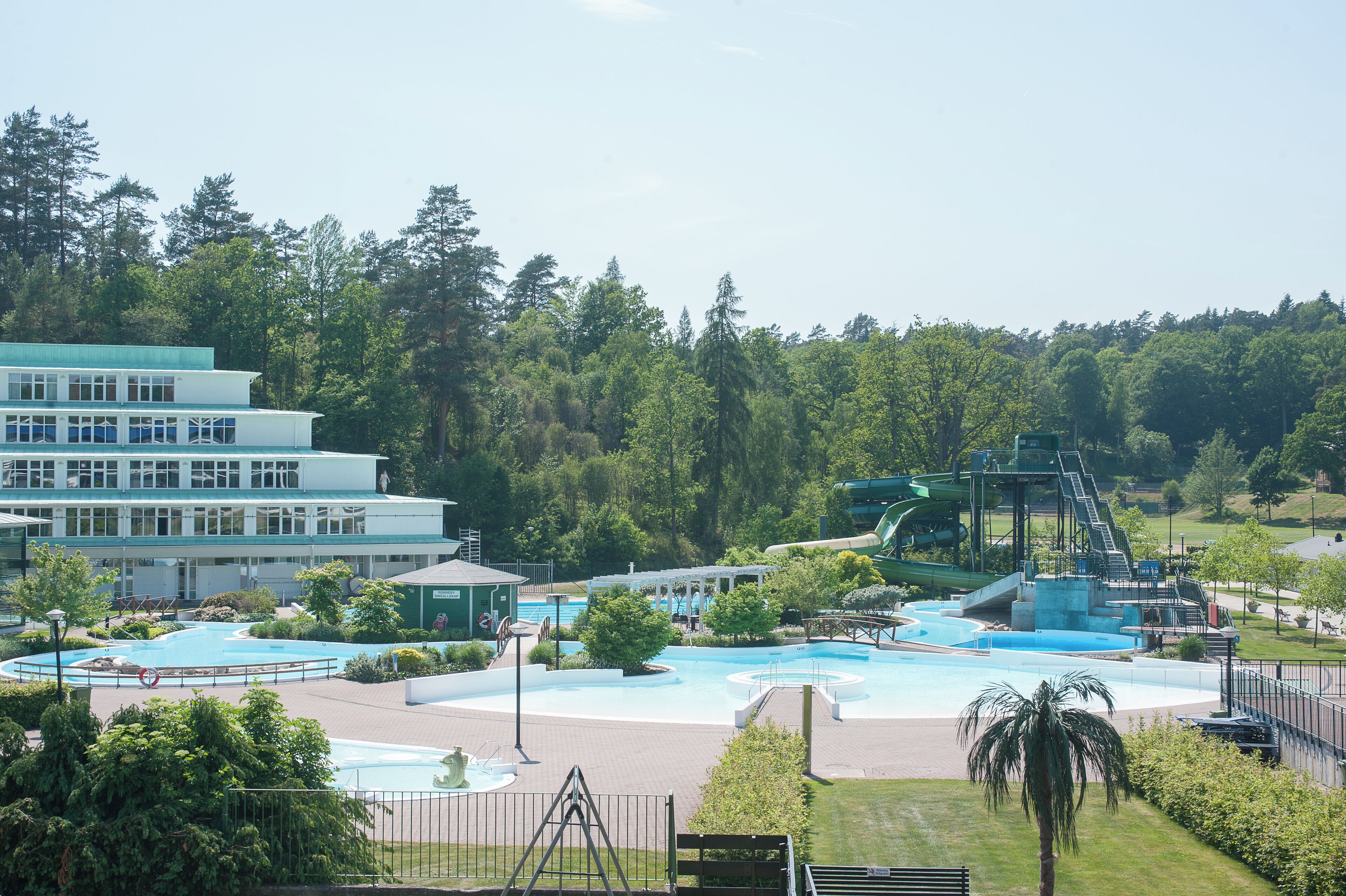 A resort with multiple swimming pools, a water slide, and a building with a multi-story structure.