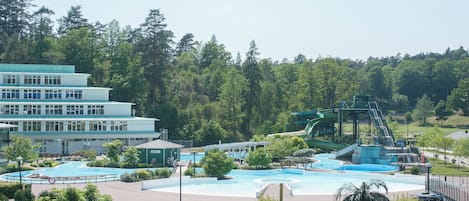 Un complejo turístico con varias piscinas, un tobogán acuático y un edificio de varias plantas.