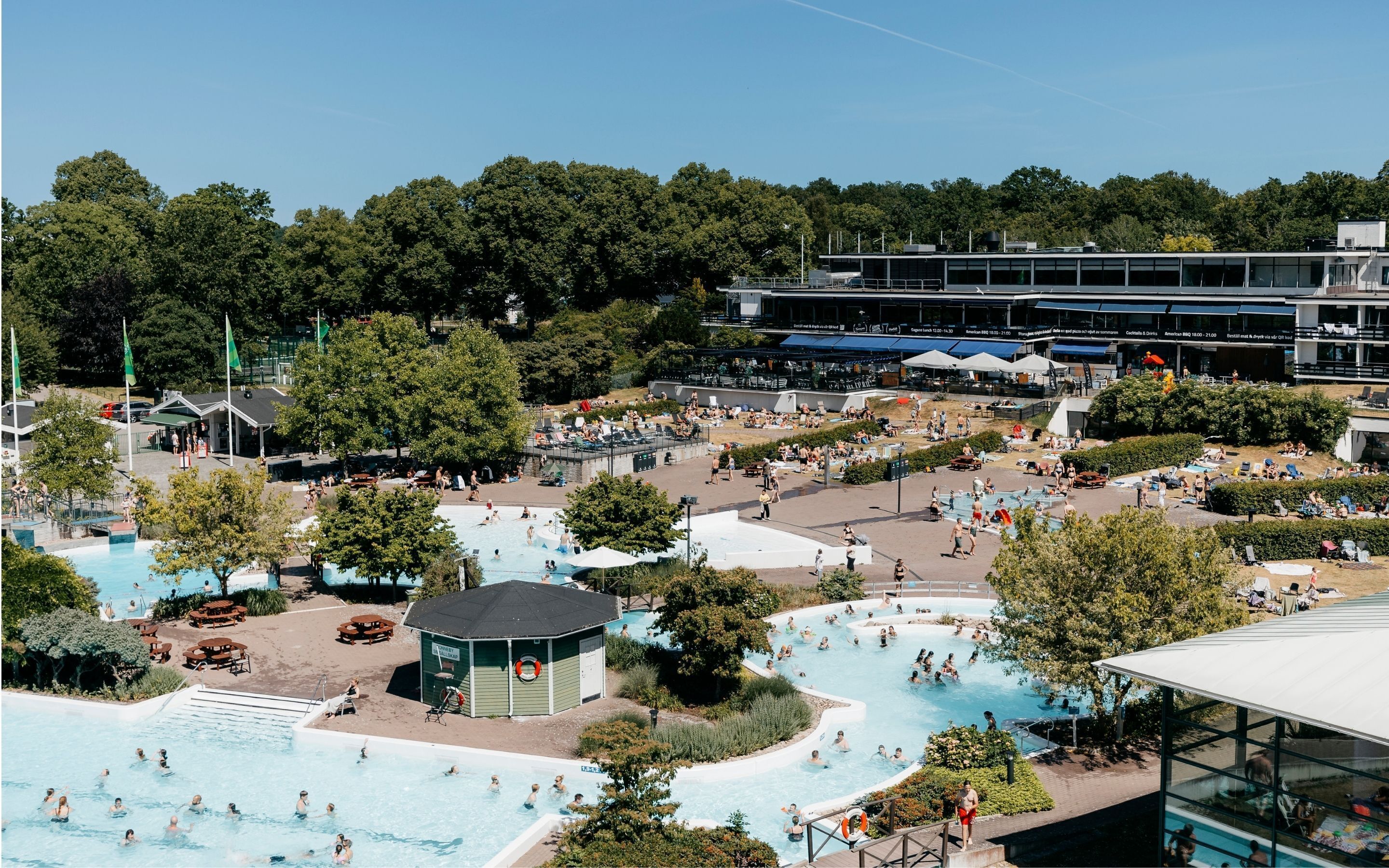 A resort with multiple swimming pools, outdoor seating areas, and a large building with outdoor seating.
