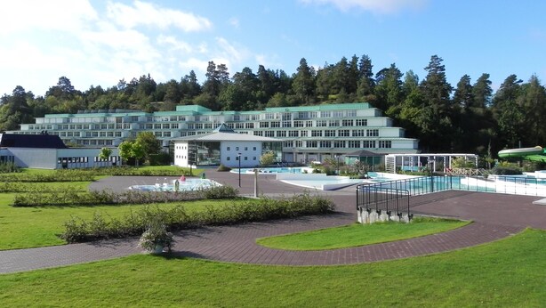 Ein großes Hotel mit mehreren Gebäuden, einem Poolbereich und einem gepflegten Rasen.