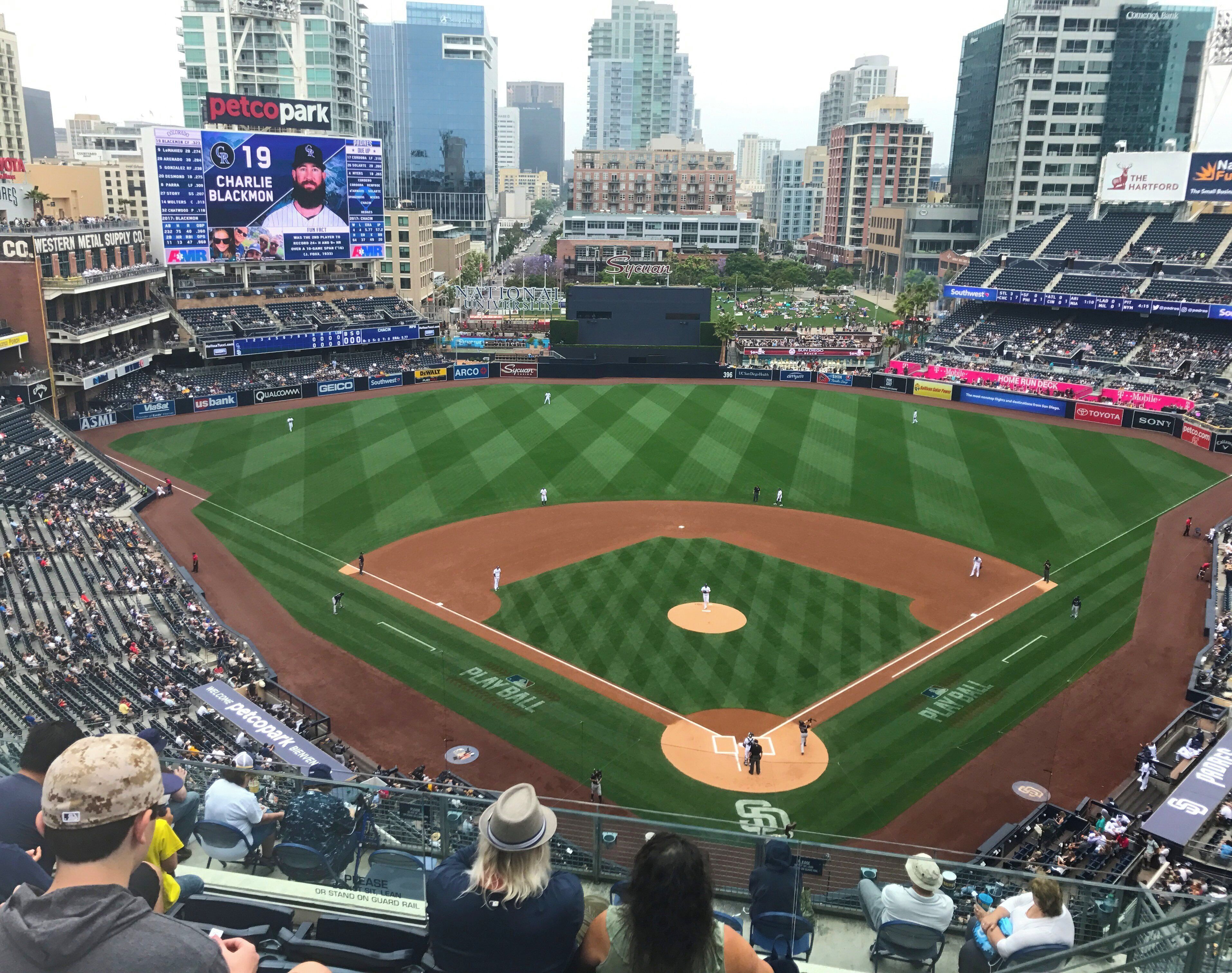Un estadio de béisbol con varios niveles de asientos, un marcador digital grande y anuncios.