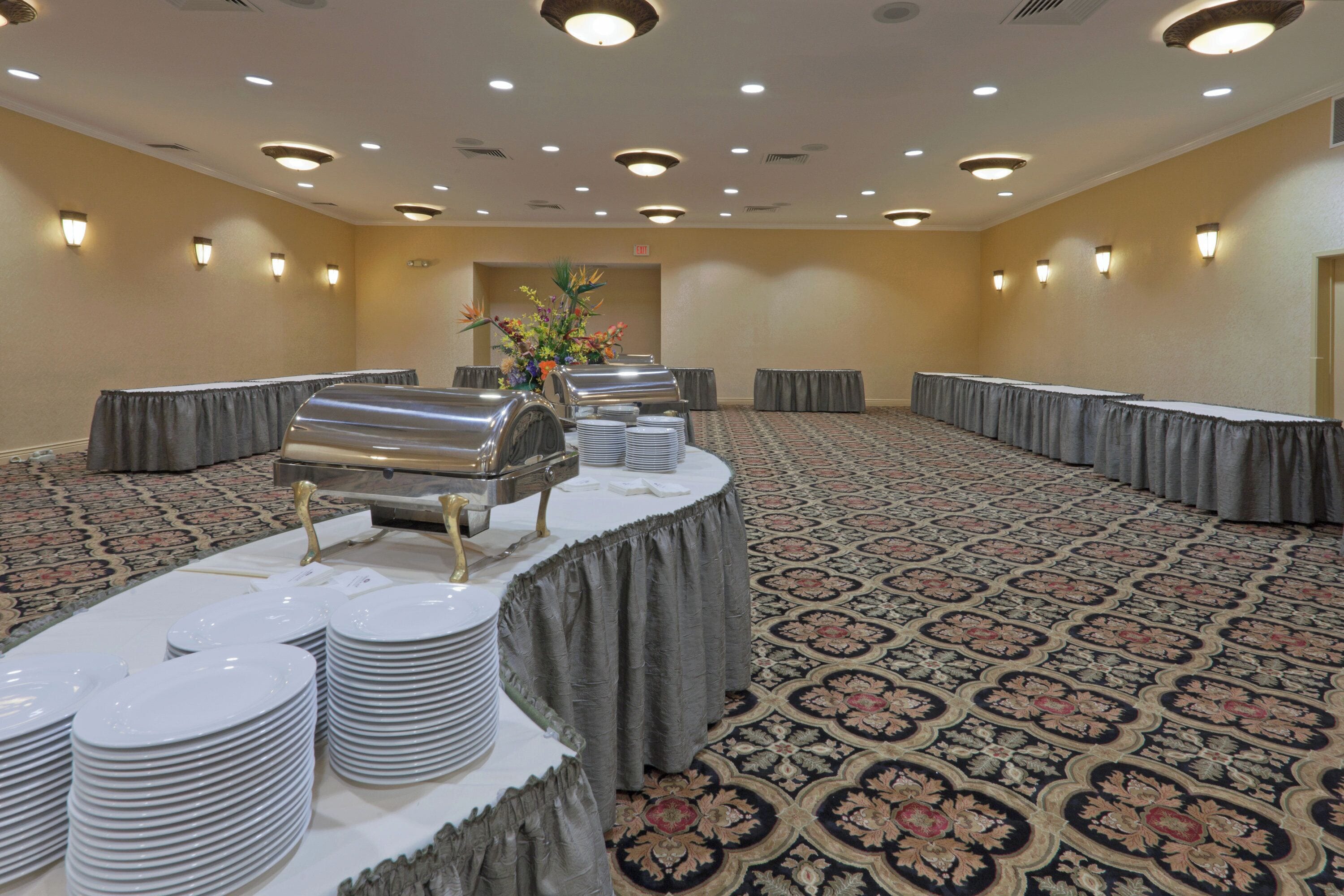 A banquet hall with round tables, buffet stations, and a patterned carpet.