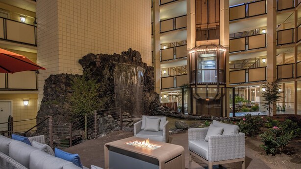 A hotel lobby with a waterfall feature, outdoor seating area, and multiple floors with balconies. - Crowne Plaza San Diego - Mission Valley by IHG (San Diego)