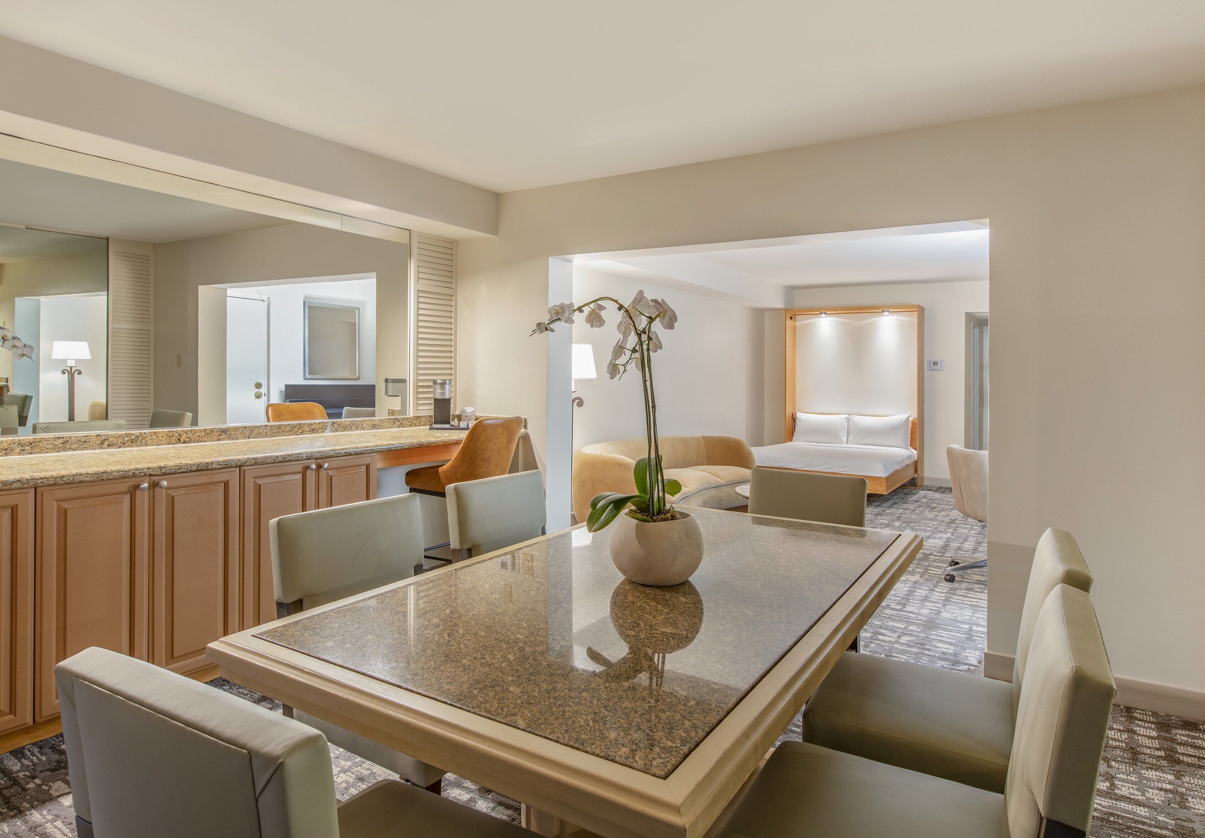 A hotel room with a dining area, a bed, and a bathroom.