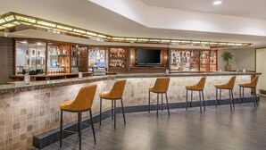 A bar area with a long counter, multiple stools, and a television screen. - Crowne Plaza San Diego - Mission Valley by IHG (San Diego)