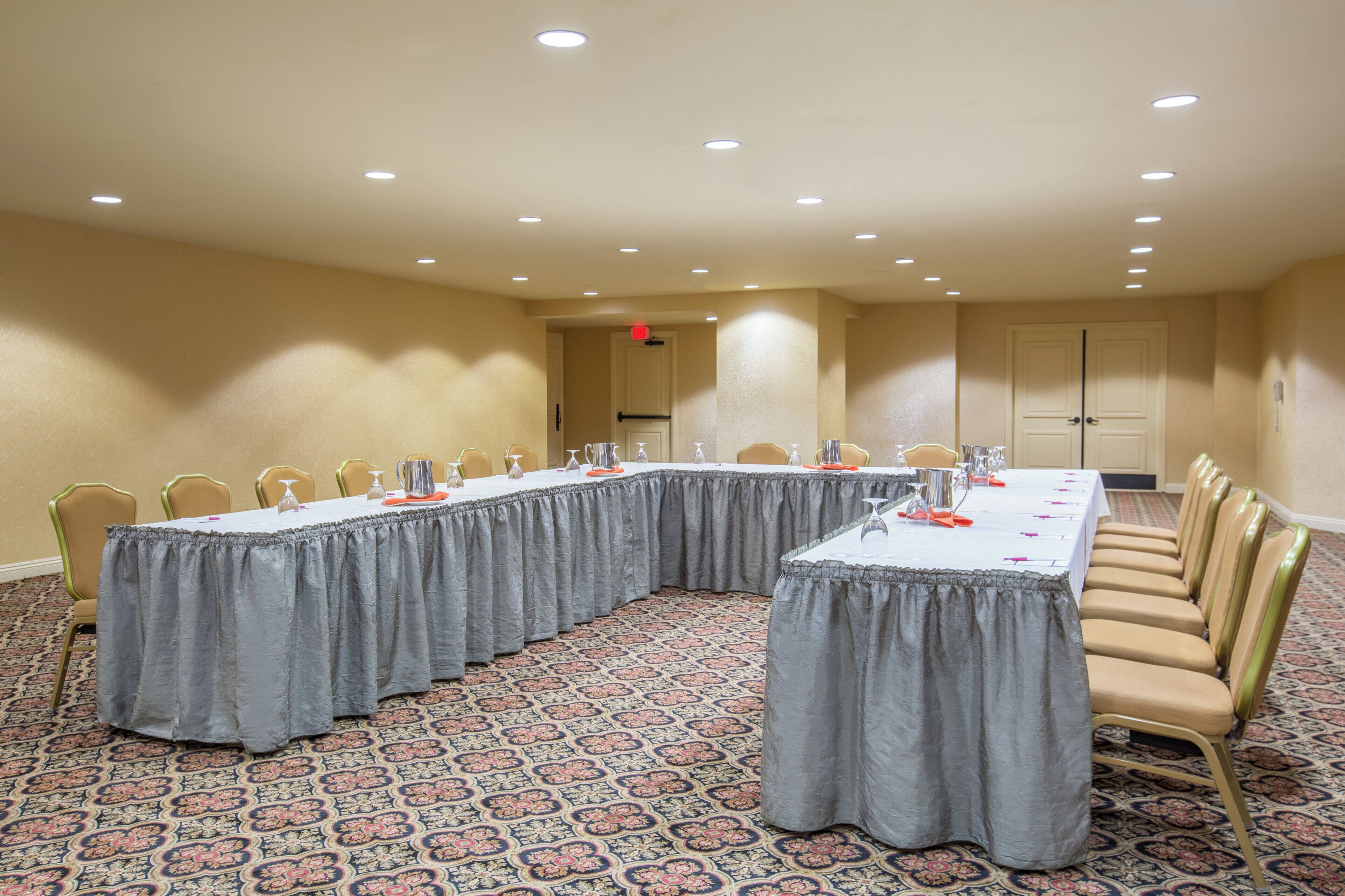 A conference room with a long table, chairs, and a patterned carpet.