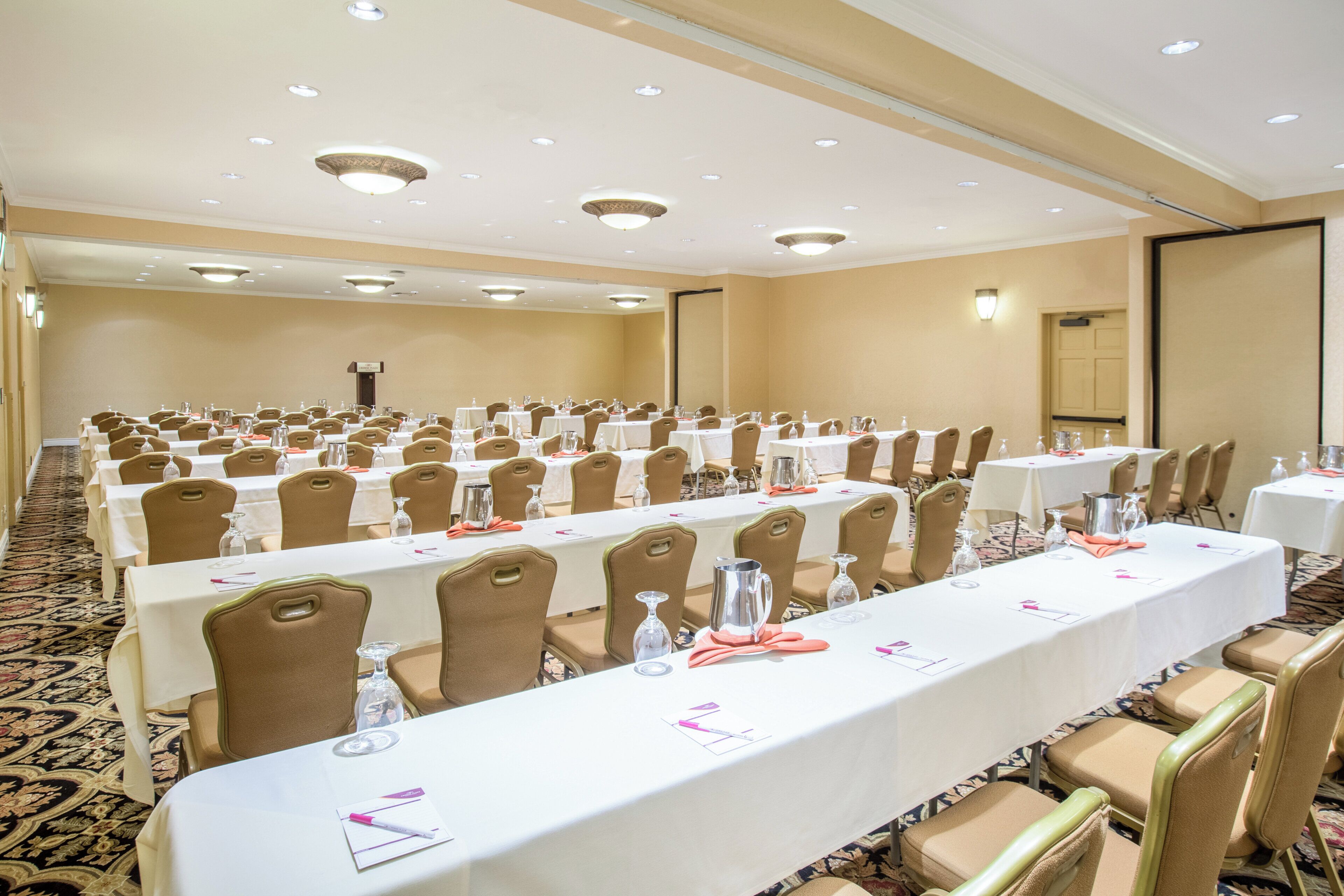 A conference room with multiple tables and chairs, equipped with water bottles and glasses.
