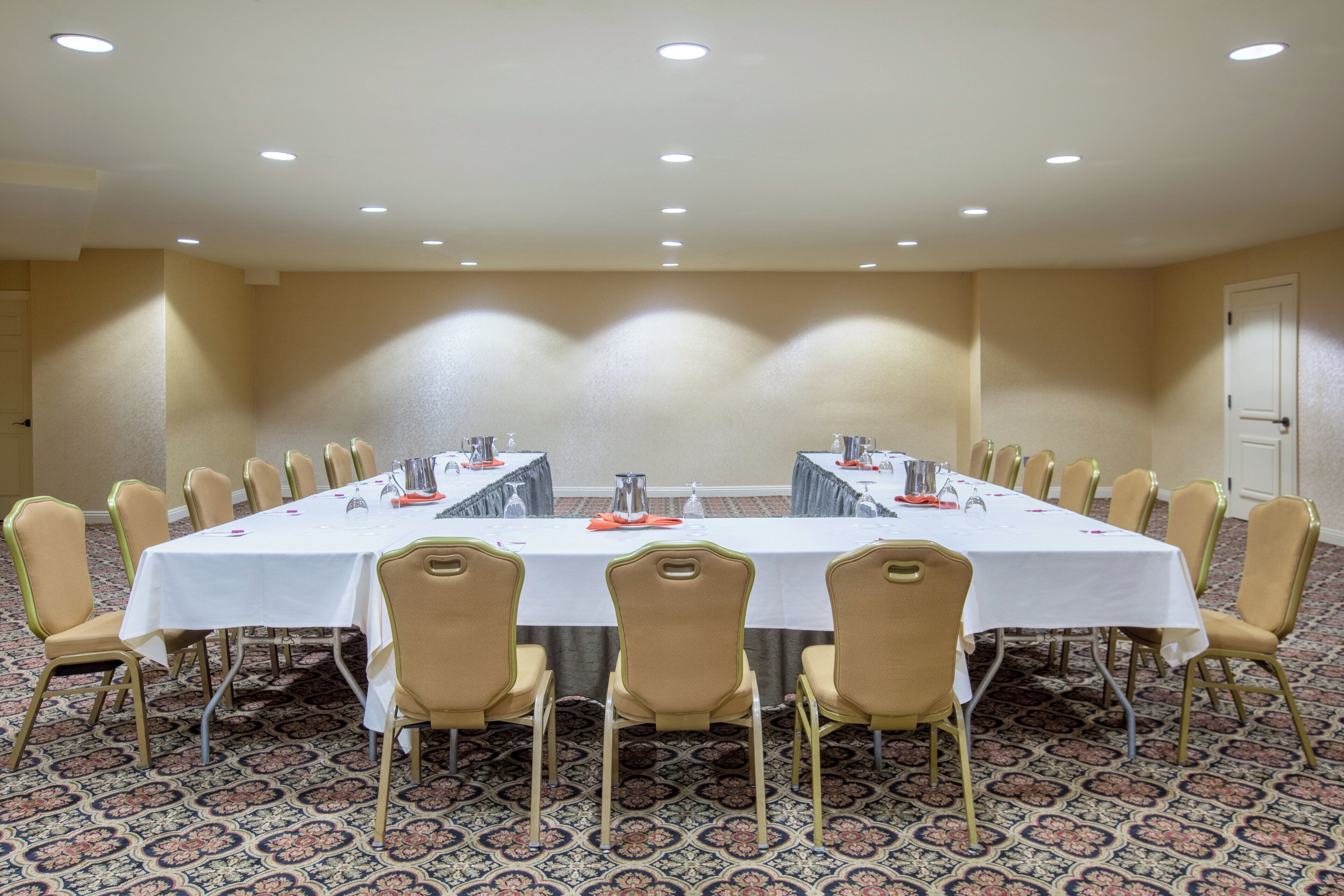 Un salón de conferencias con una mesa larga, sillas y suelo alfombrado.