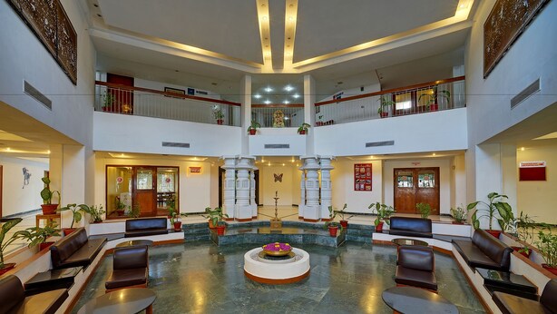 A spacious lobby with a central fountain, seating areas, and potted plants.