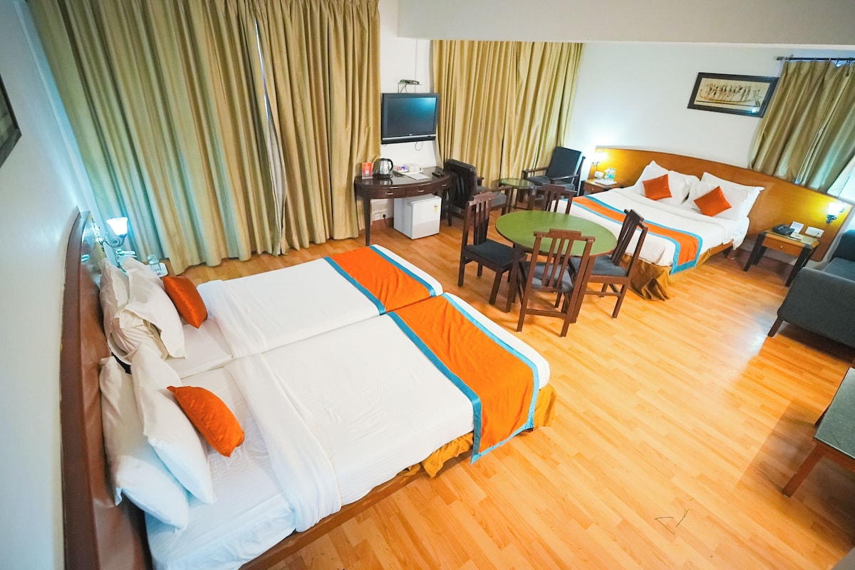 A hotel room with two beds, a desk, a chair, a television, and a small table.