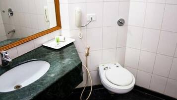 A bathroom with a white toilet, a sink with a green countertop, and a mirror above the sink.