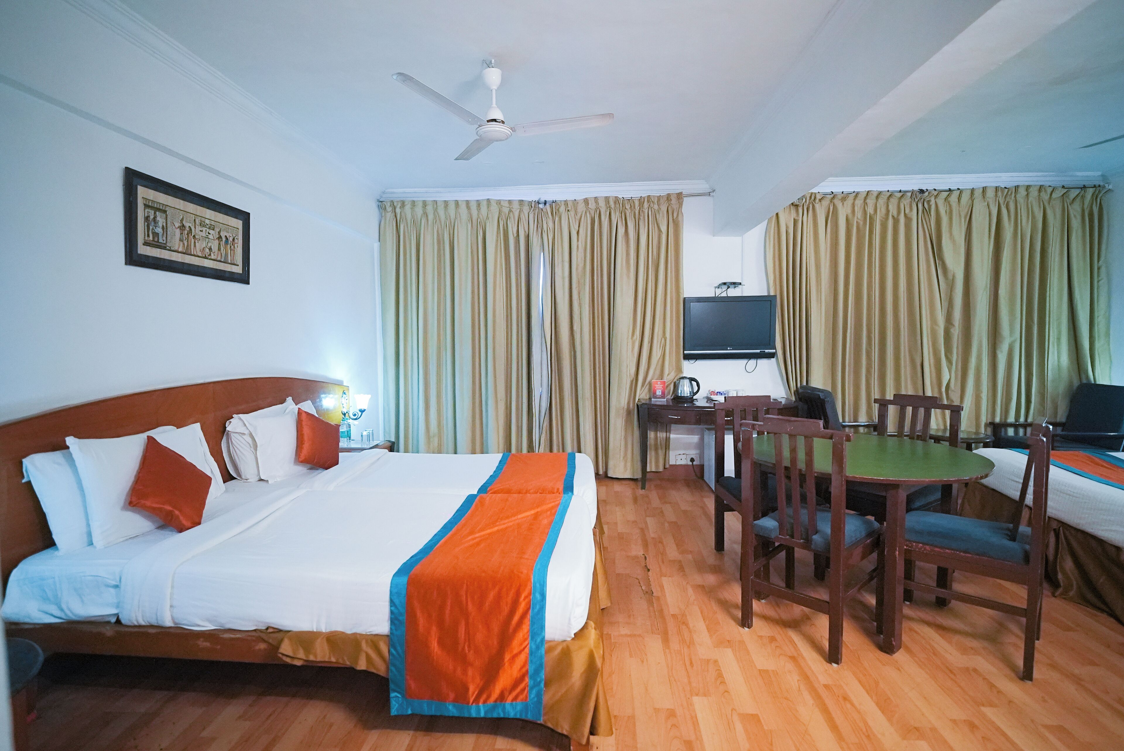 A hotel room with a bed, a desk, a chair, a television, and curtains.