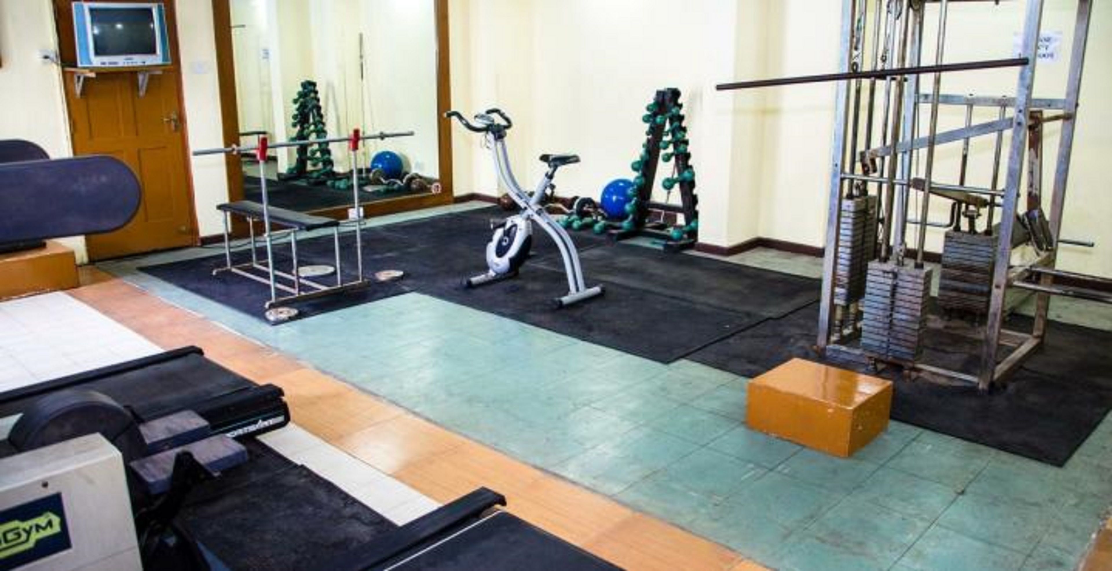 Un gimnasio con equipo de ejercicio, cinta de correr y zona de levantamiento de pesas.