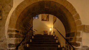 Una escalera de piedra con faroles, que lleva a una habitación con una lámpara y un cuadro en la pared.