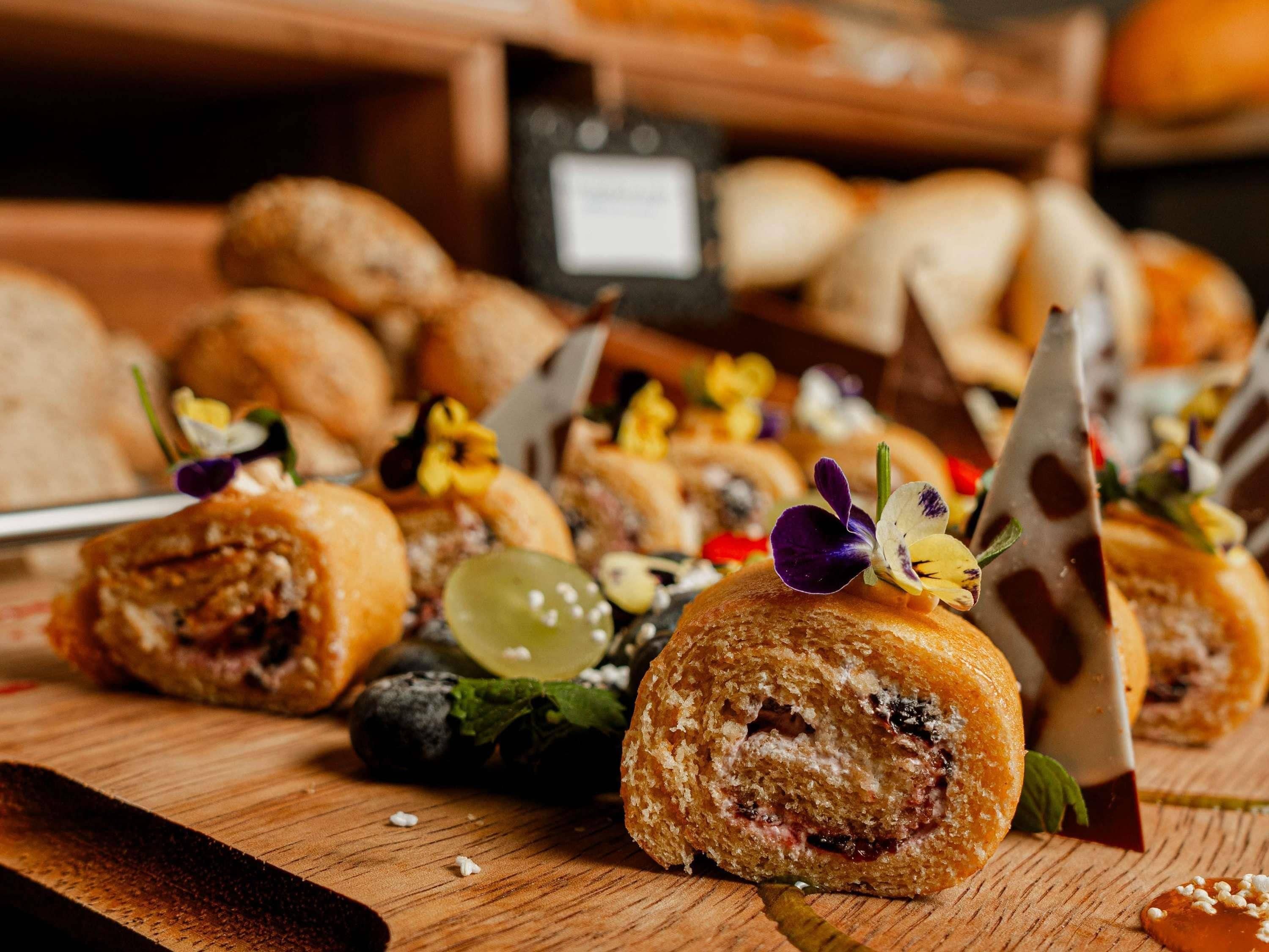 A variety of pastries and desserts on a wooden surface, likely in a bakery or cafe setting.