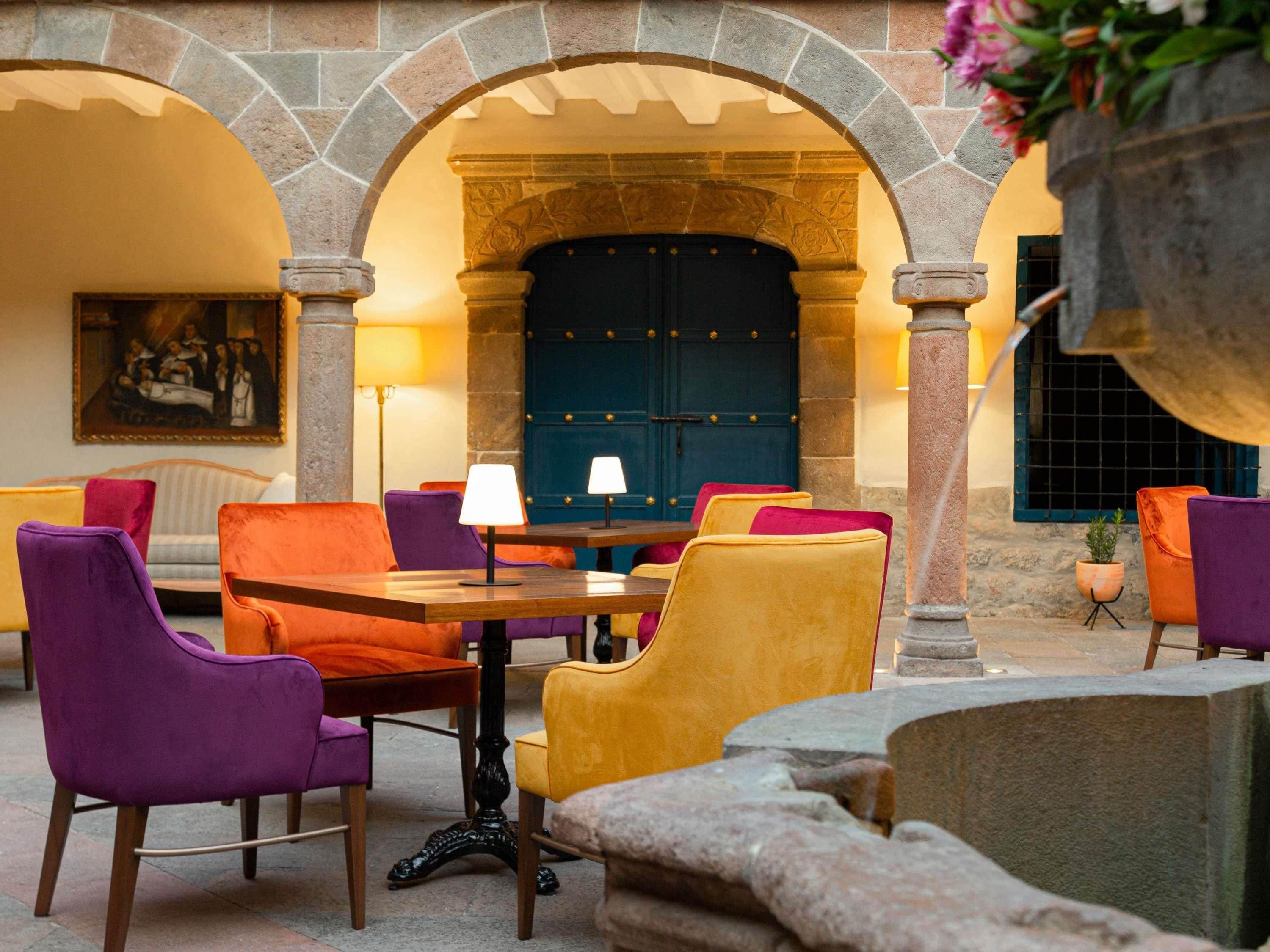 A cozy seating area with a table and chairs, a blue door, and a stone archway.