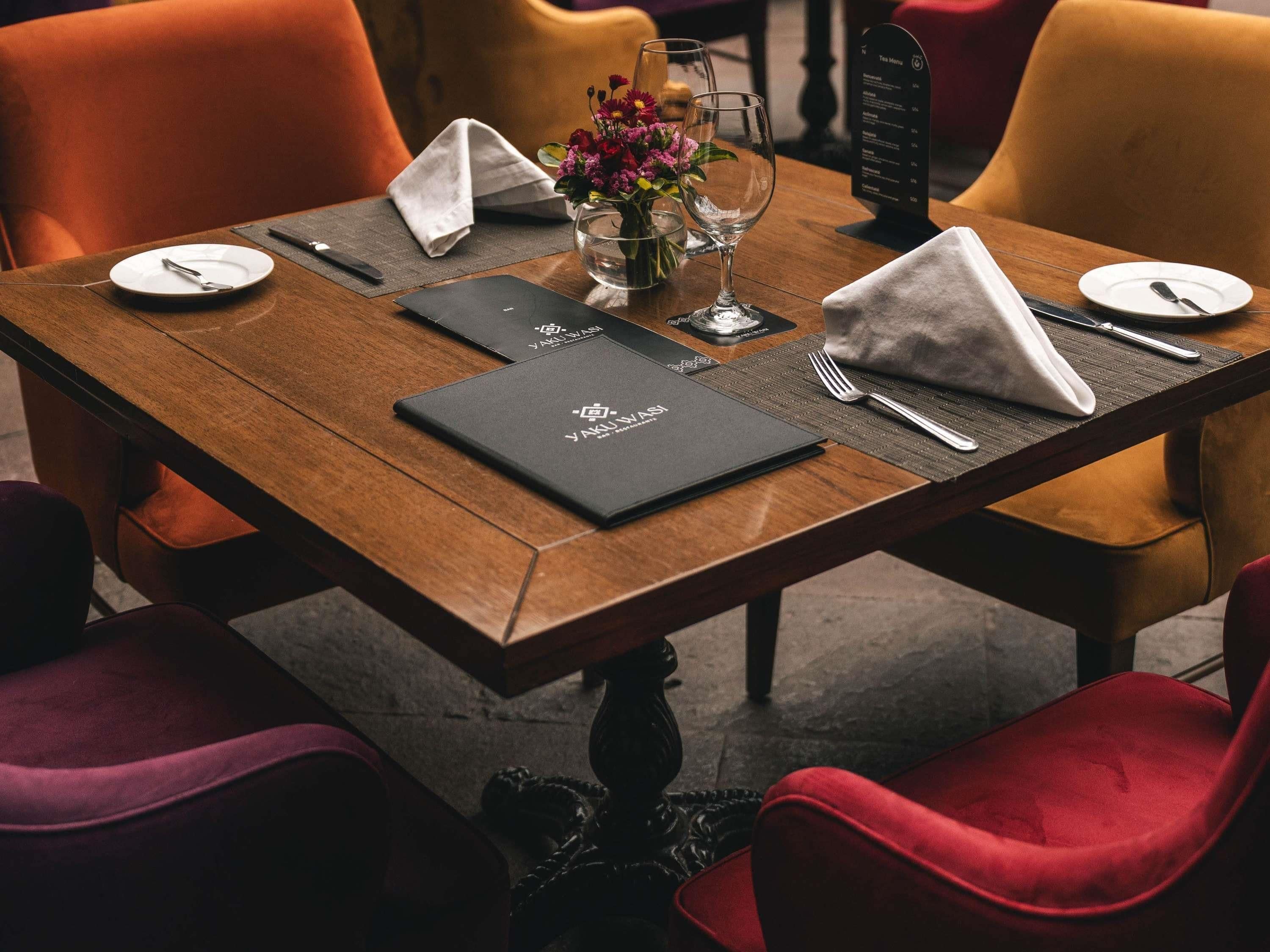 Una mesa de restaurante dispuesta con un menú, un florero y una copa de vino.