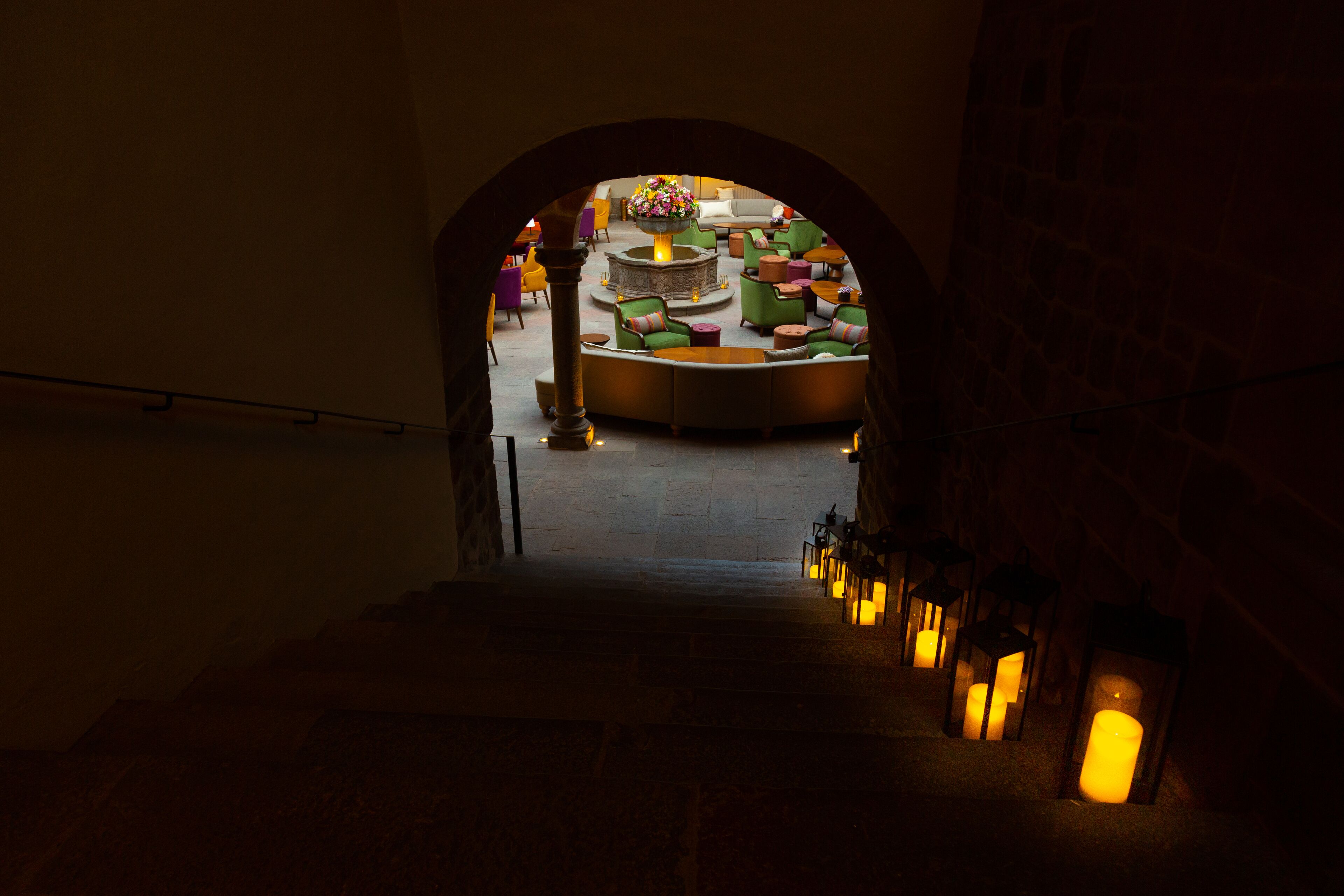 A staircase leading to a lobby with a round seating area and a fire feature.