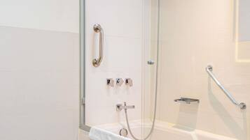 Un baño moderno con cabina de ducha de vidrio, ducha de mano, barra de apoyo y toallero.
