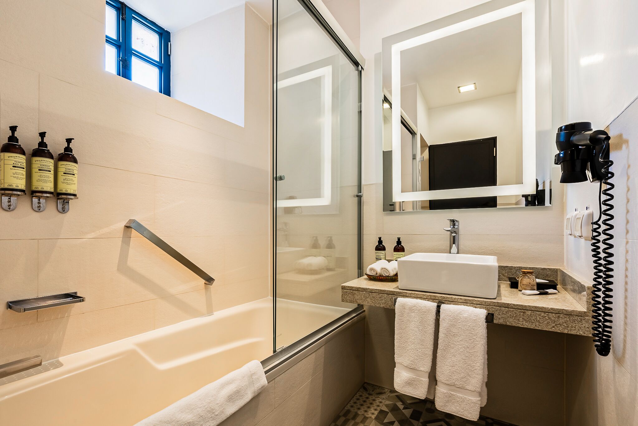 Un baño moderno con ducha acristalada, tocador con lavabo y un espejo grande.