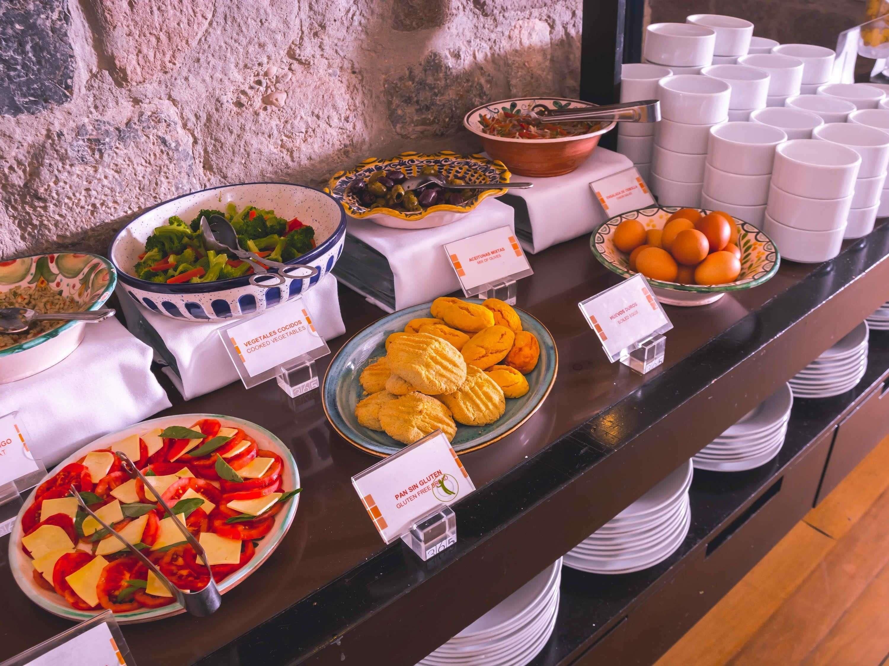 Un buffet proposant une variété de plats, dont des légumes, des œufs et des options sans gluten, chaque plat étant clairement identifié.