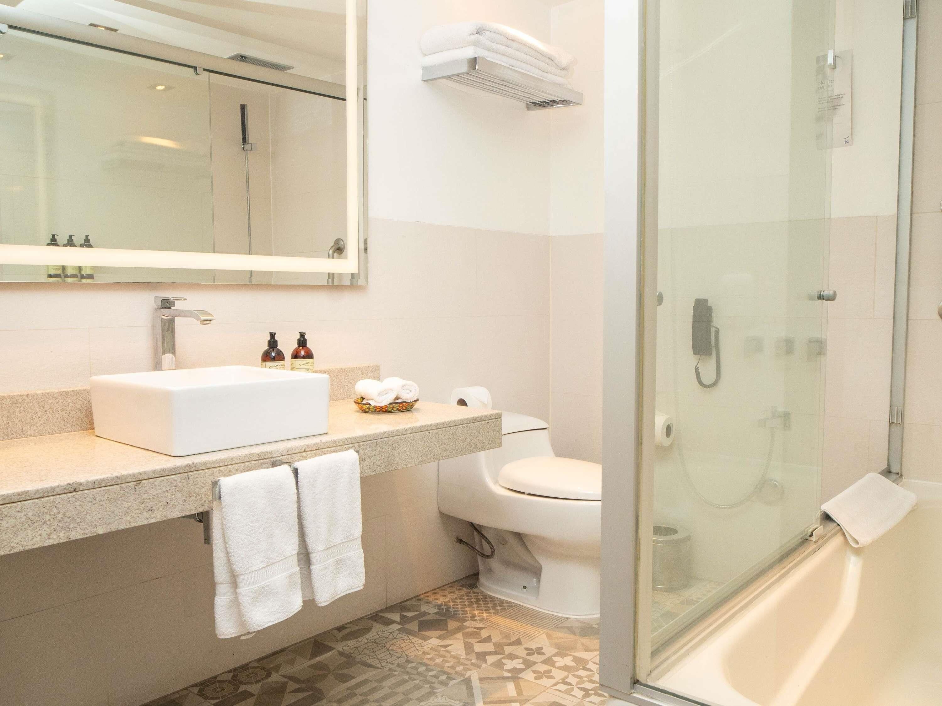 A modern bathroom with a glass-enclosed shower, a white sink, and a toilet.