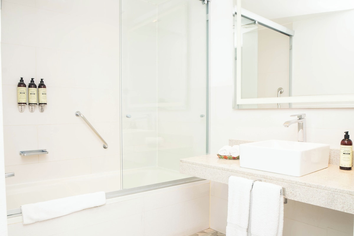 A modern bathroom with a glass-enclosed shower, a white sink, and a large mirror.