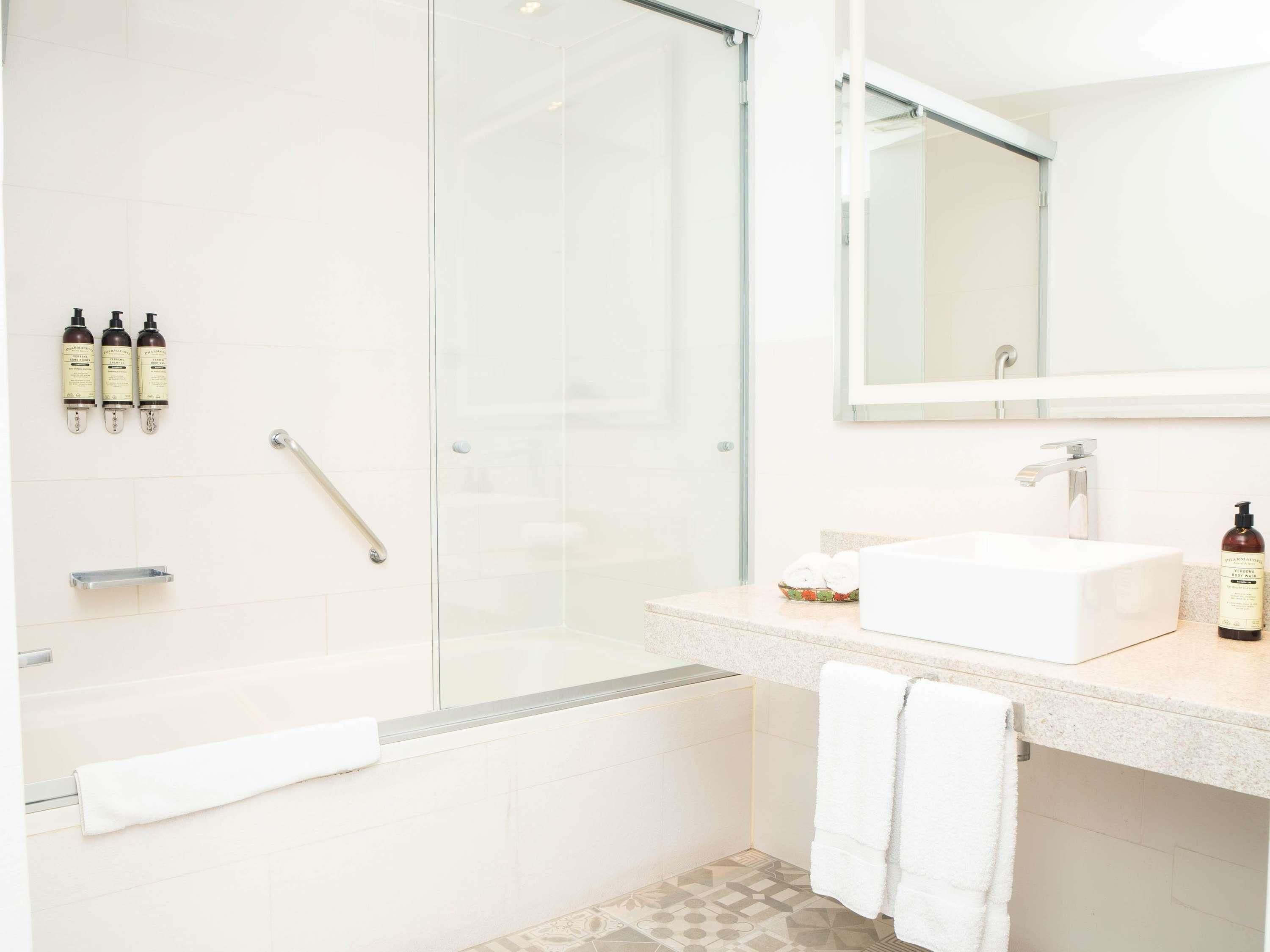 A modern bathroom with a glass-enclosed shower, a white sink, and a mirror above it.