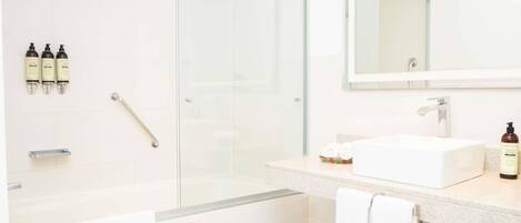 A modern bathroom with a glass-enclosed shower, a white sink, and a mirror above it.
