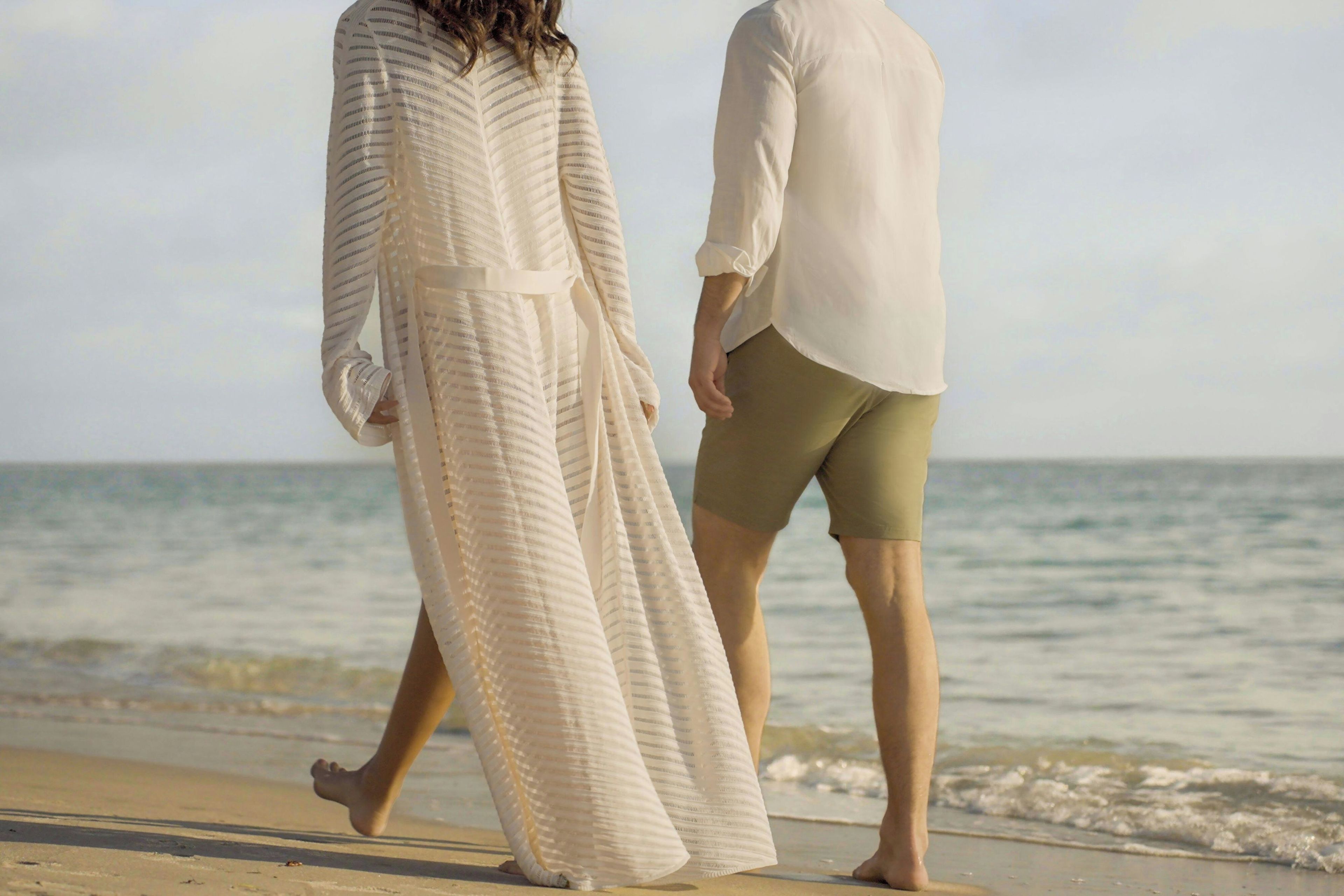 Una pareja caminando por la playa, con el océano al fondo.