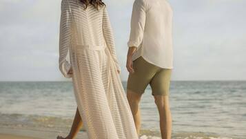 Una pareja caminando por la playa, con el océano al fondo.