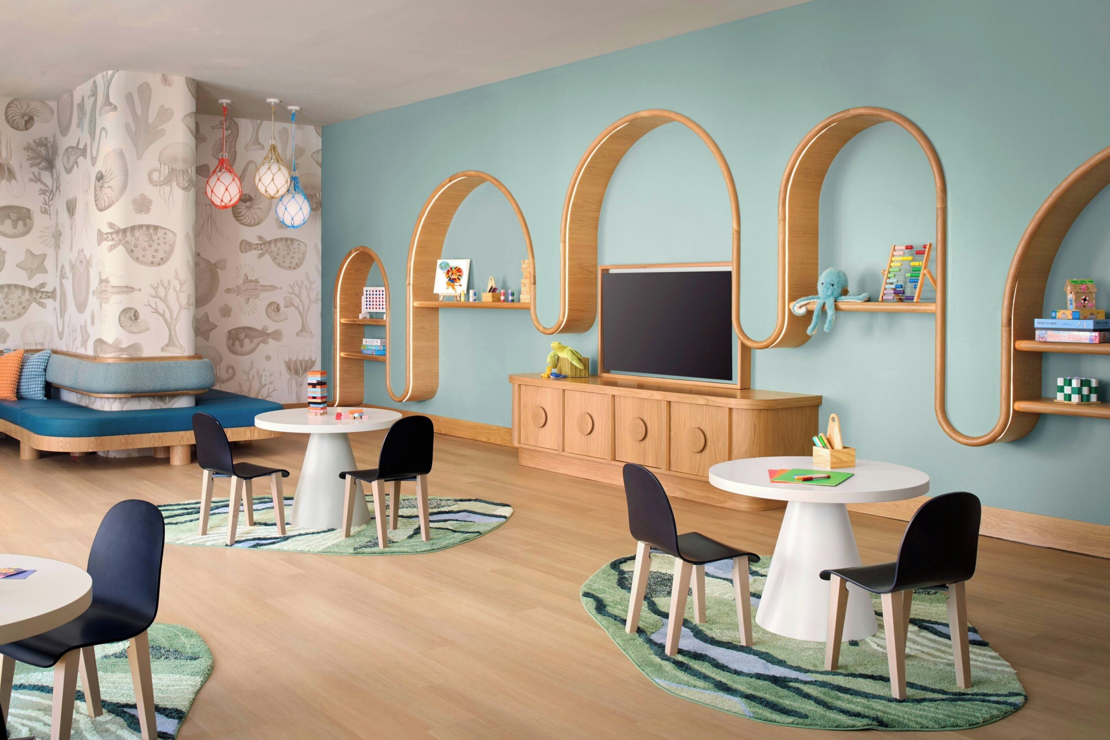 A children's playroom with a large TV, wooden shelves, and a blue wall.