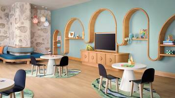 A children's playroom with a large TV, wooden shelves, and a blue wall.