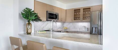 A modern kitchen with a central island, stainless steel appliances, and wooden cabinets.