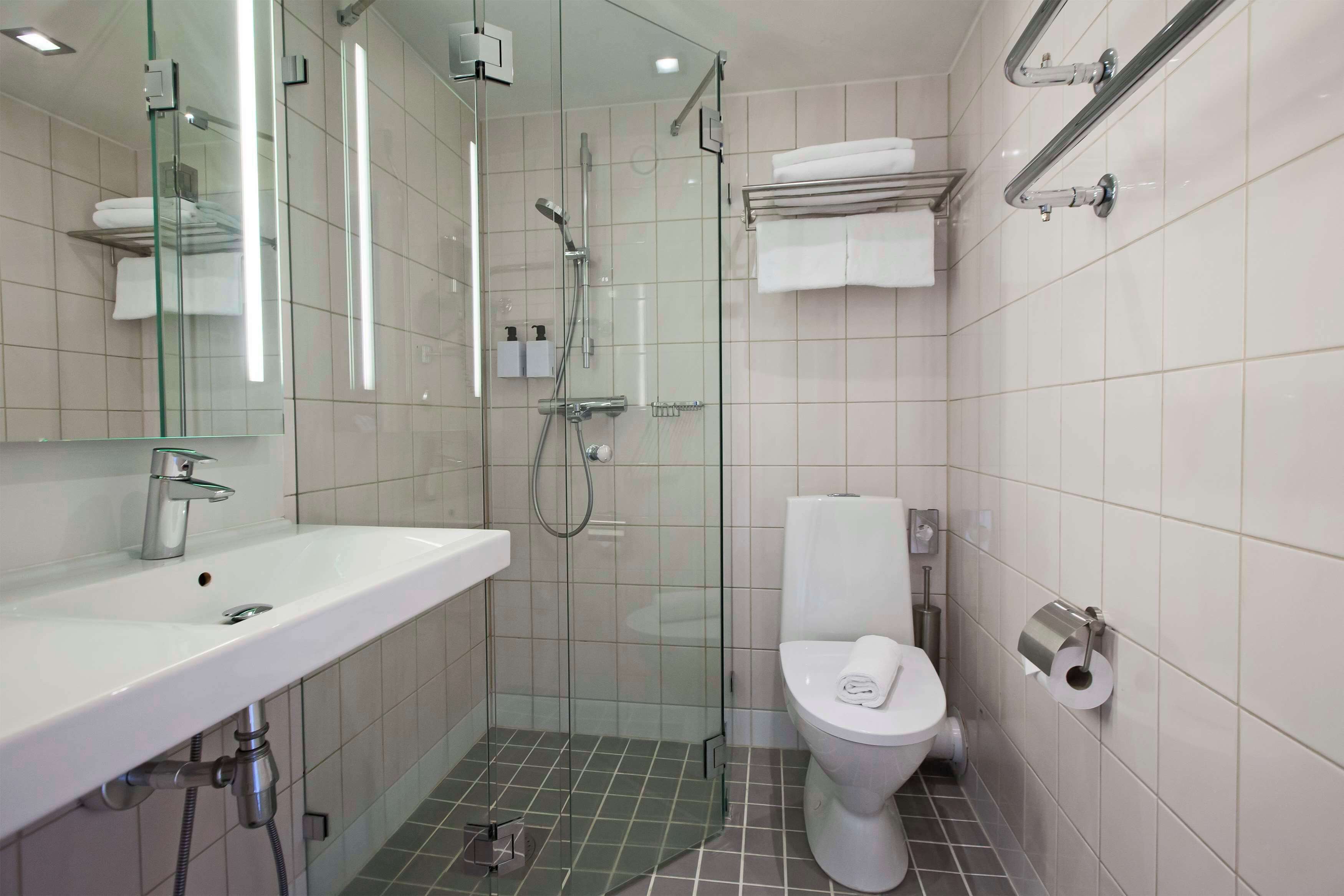 Un baño moderno con ducha envuelta en vidrio, un lavamanos blanco y un inodoro.