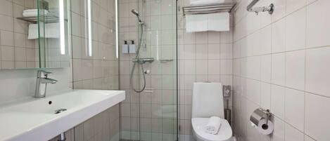 Un baño moderno con ducha envuelta en vidrio, un lavamanos blanco y un inodoro.