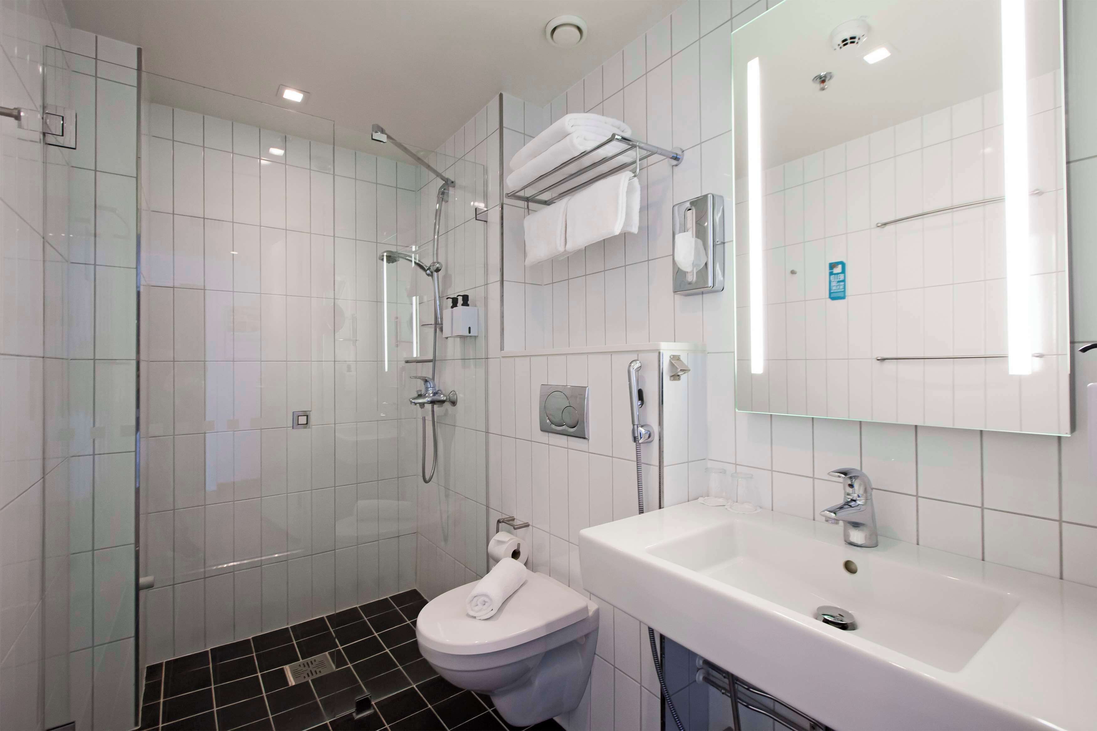 A modern bathroom with a glass shower enclosure, a white toilet, a sink with a mirror, and a towel rack.