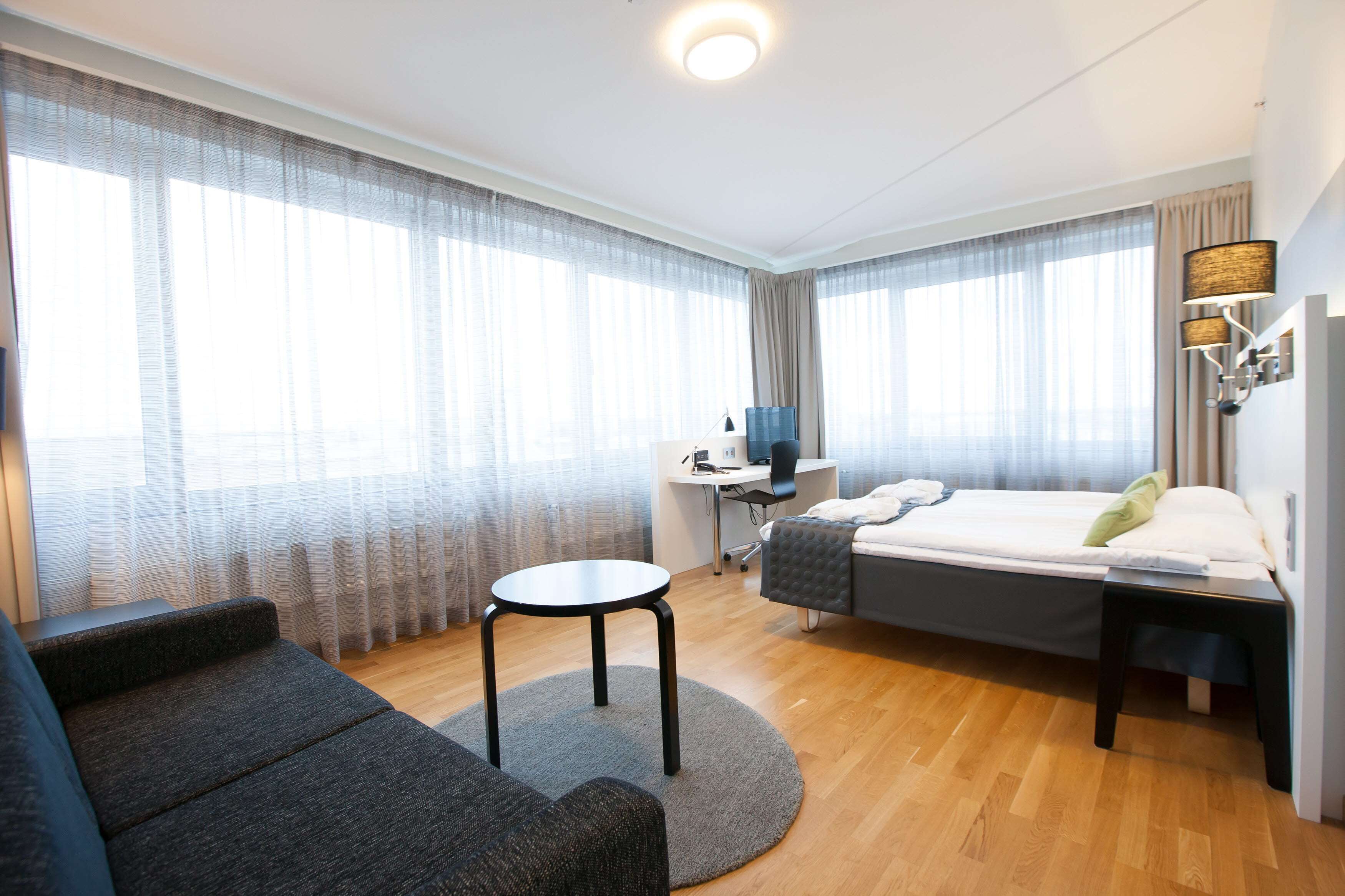 Une chambre d’hôtel moderne équipée d’un lit, d’un bureau, d’une chaise et d’un canapé.