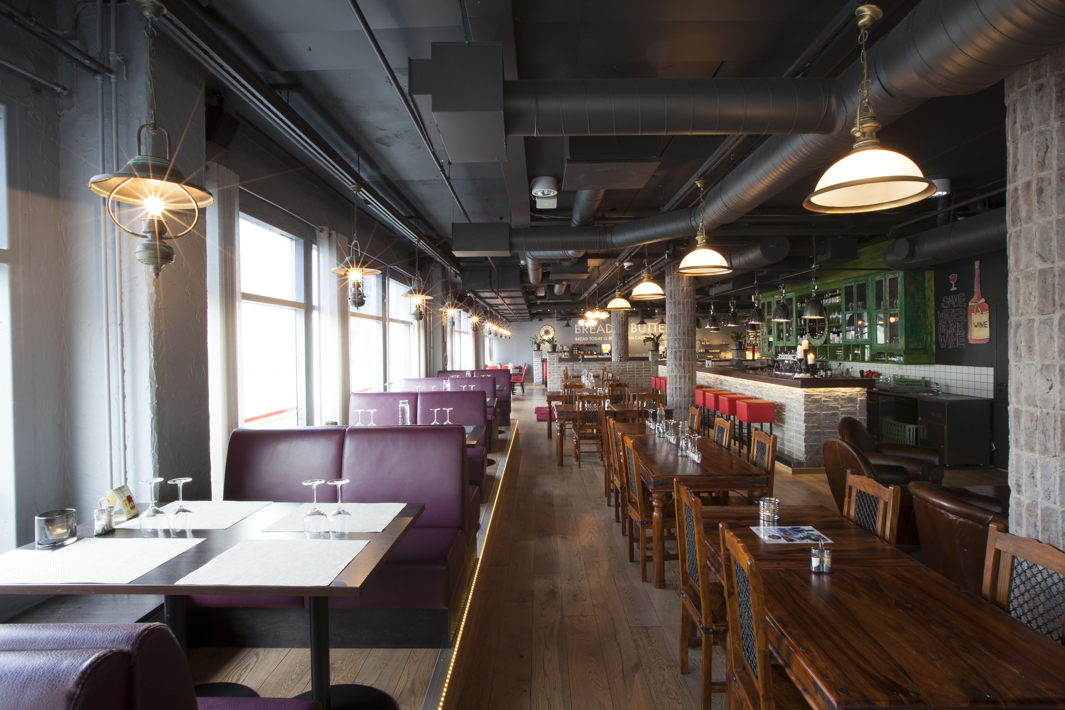 A restaurant interior with high tables, booths, and a bar area.