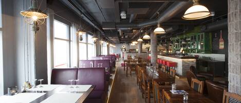 A restaurant interior with high tables, booths, and a bar area.