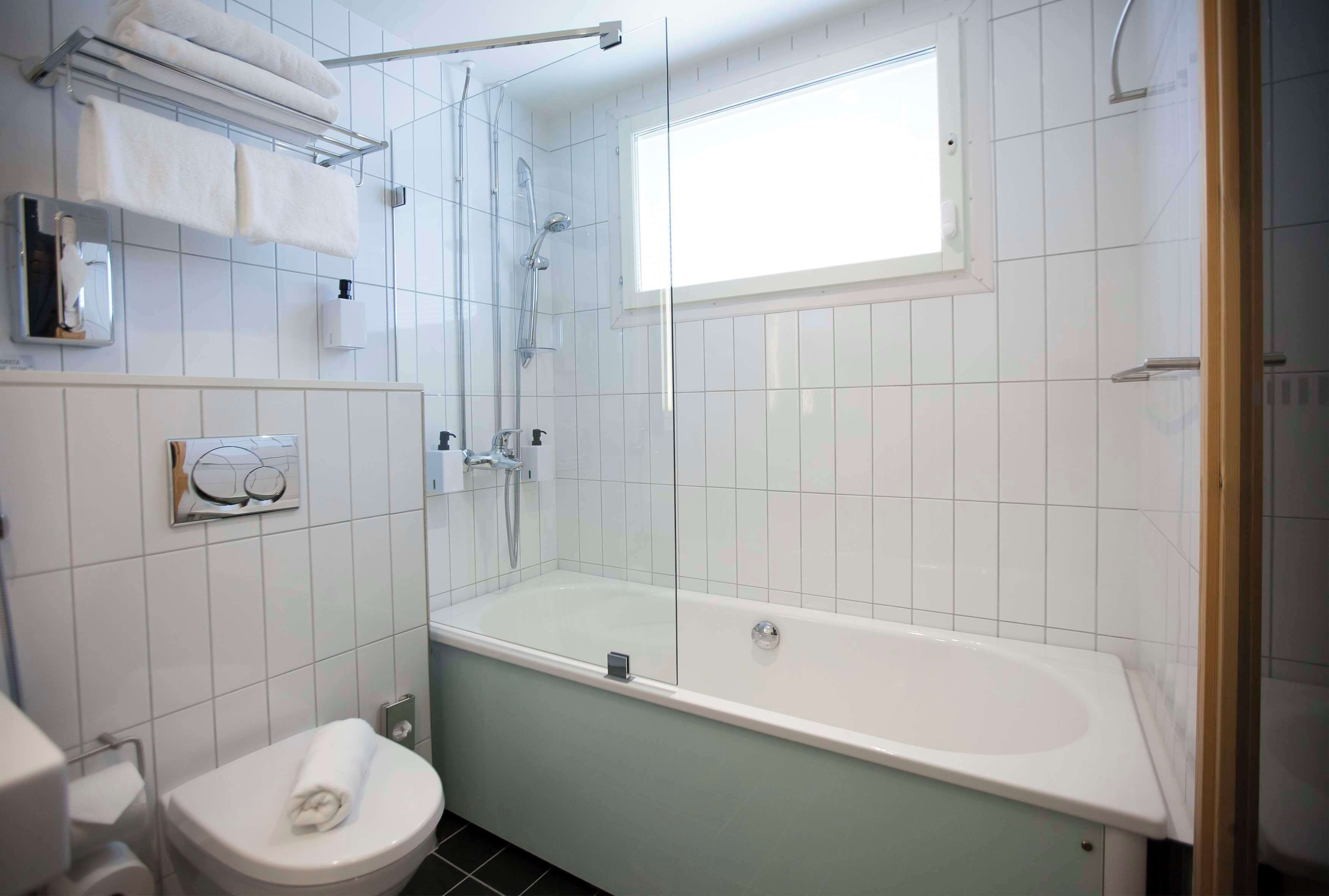 A bathroom with a bathtub, a toilet, a towel rack, and a window.