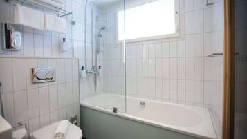 Un baño con bañera, inodoro, perchero para toallas y ventana.