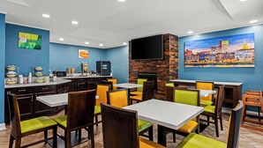 A restaurant with blue walls, a cityscape mural, and a flat-screen TV mounted on the wall.